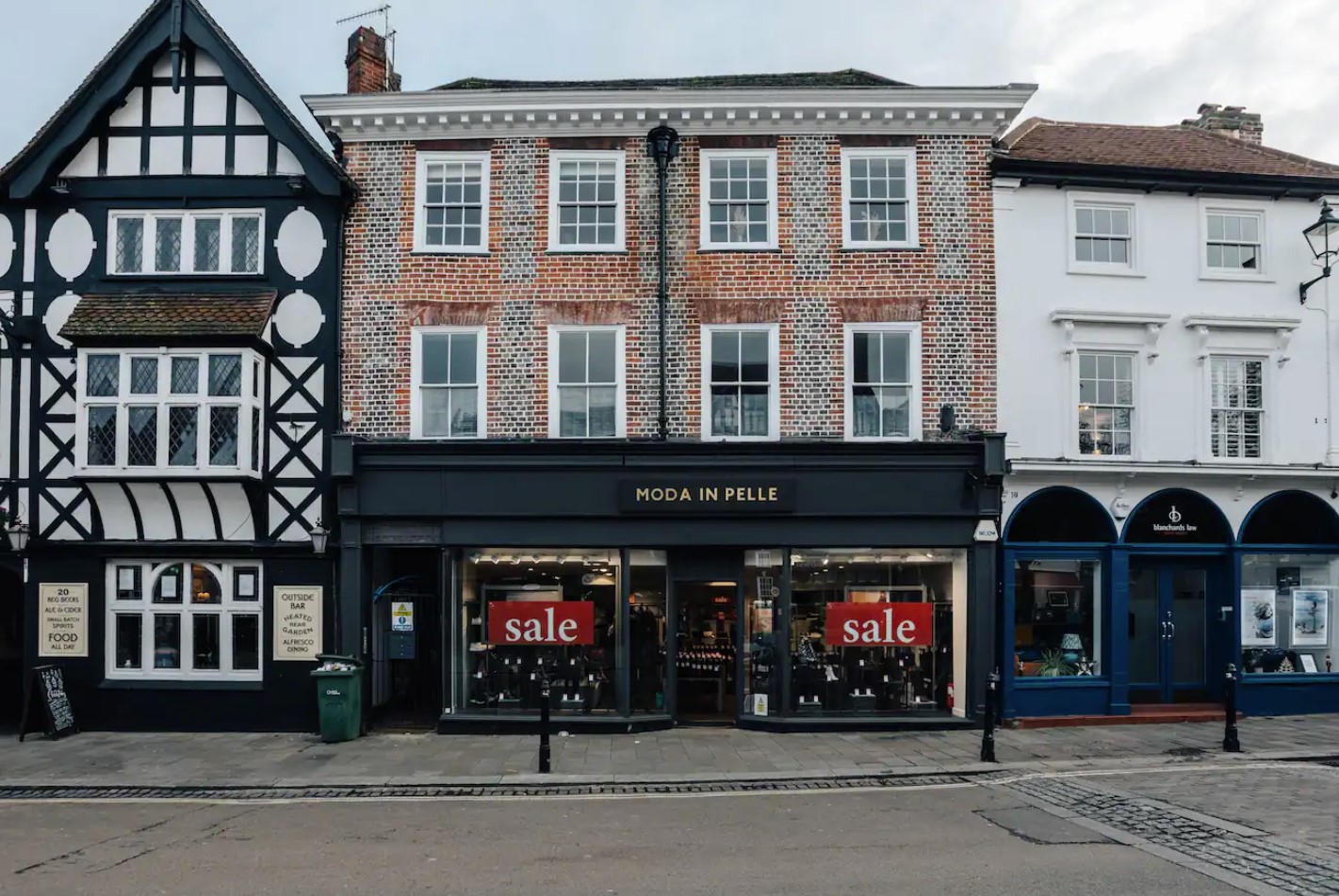 Market Place storefronts in central Henley — Tudor pub, brick building above Moda In Pelle, Georgian house with arched ground-floor